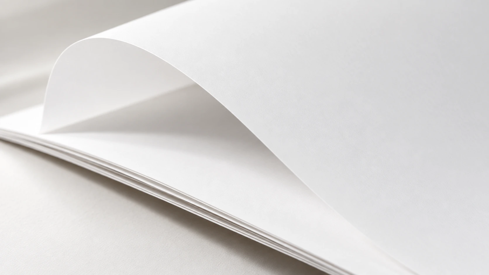 Concept image of thin, unprinted white paper sheets with a gentle bend and a fine matte surface.